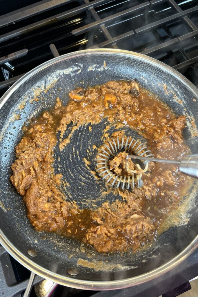 Pan with broth being mixed into roux.