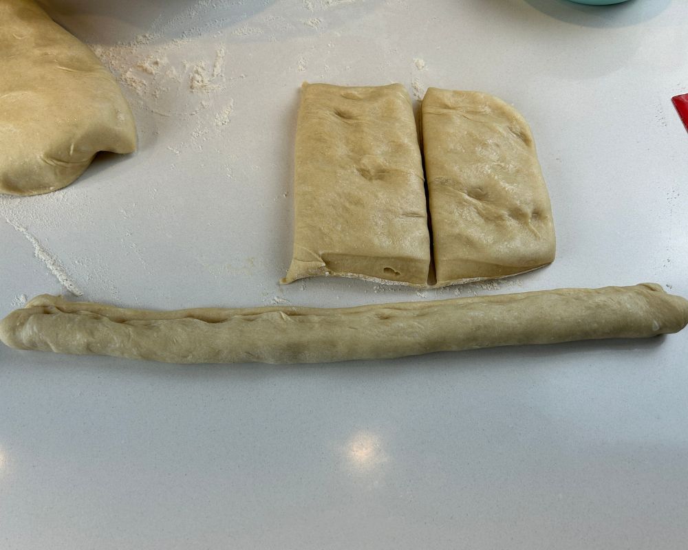 Homemade Challah dough split into three portions on a white counter. 