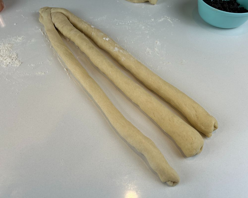 Three strand of Homemade Challah dough connected at the top. 