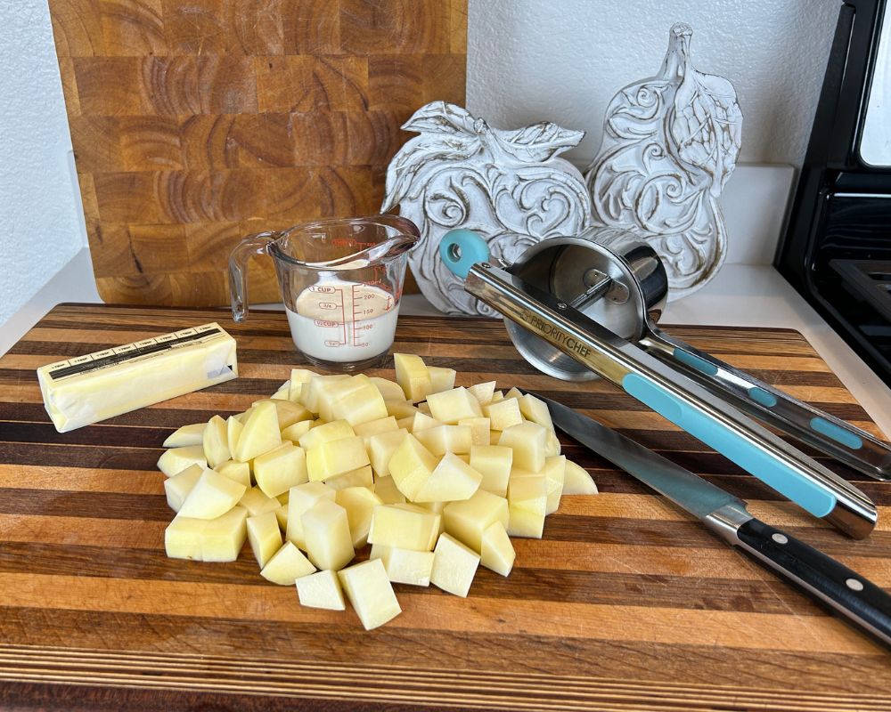 Ingredients on cutting board, including diced potatoes, butter and heavy cream.