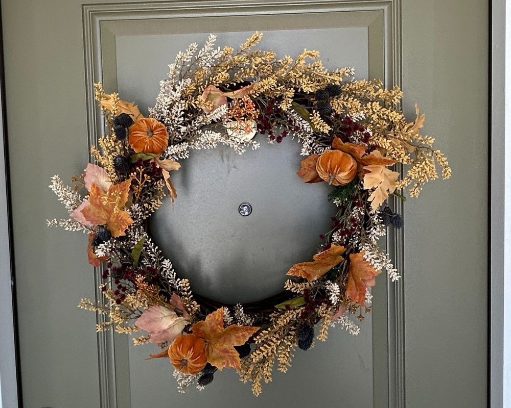 Vine wreath with a mix of floral picks in orange, cream, yellow, burgundy, green and blue.