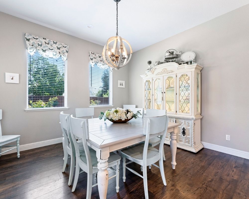 Image of dining room with gray table, aqua chairs and round chandelier over table.