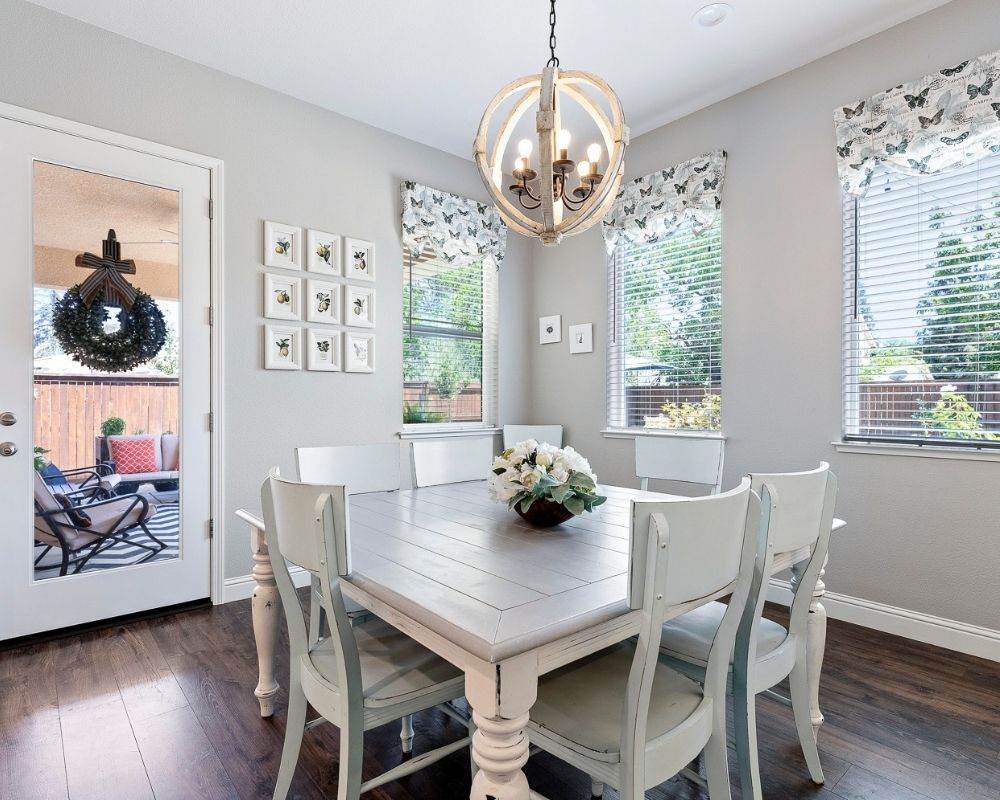 Image of dining room with gray table, aqua chairs and round chandelier over table.