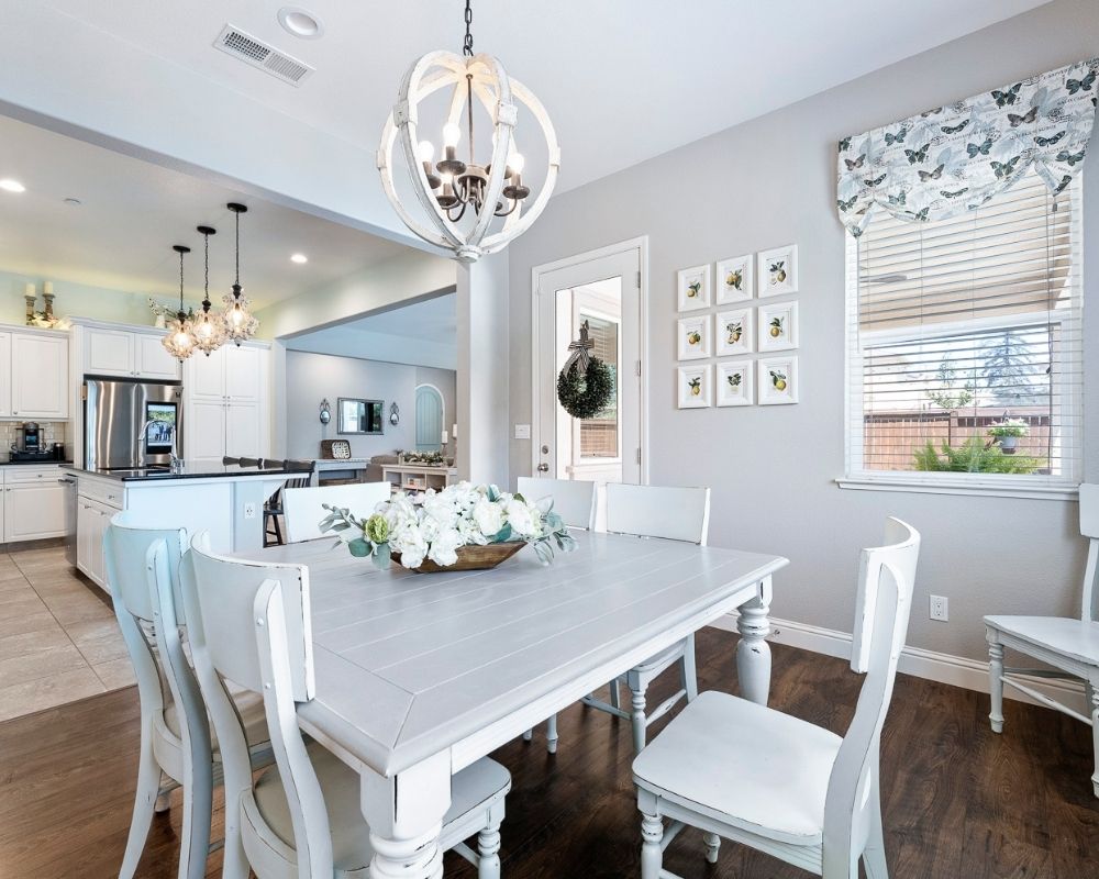 Image of dining room with gray table, aqua chairs and round chandelier over table.