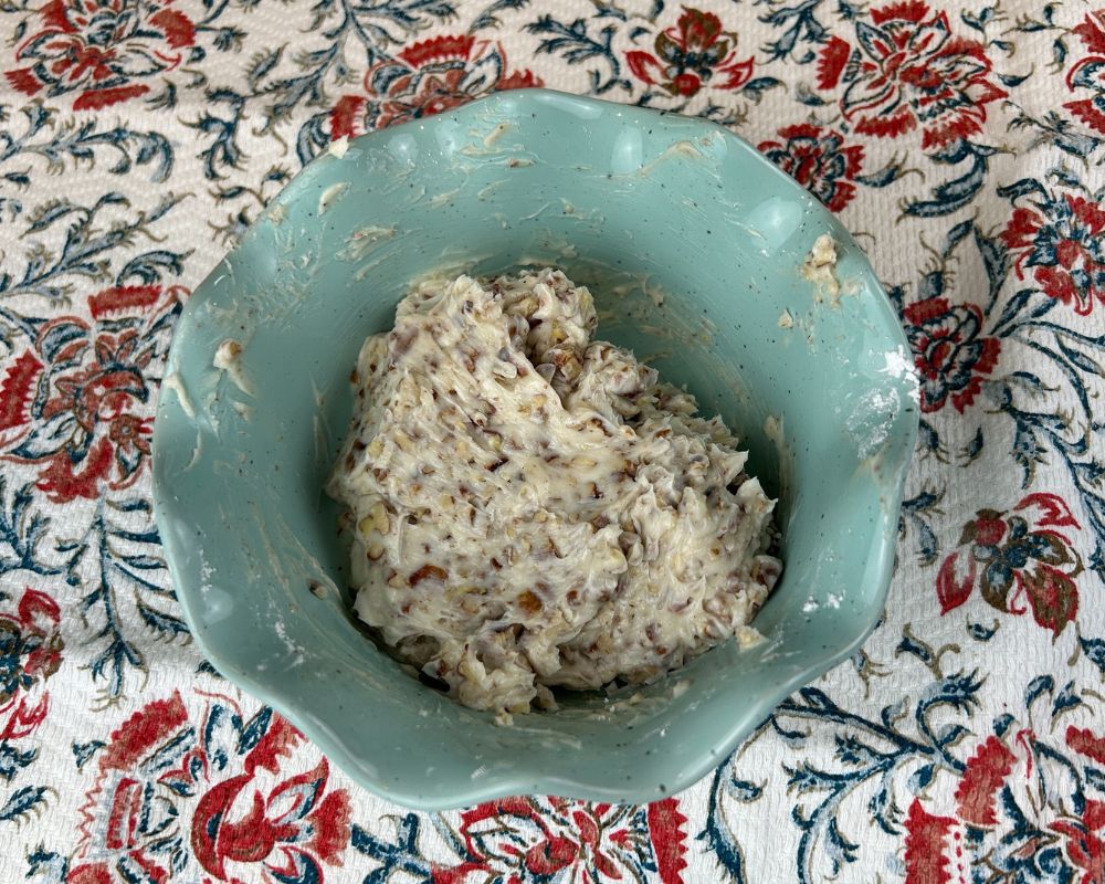 Aqua dish with chopped toasted pecans, softened butter and powdered sugar mixed together.