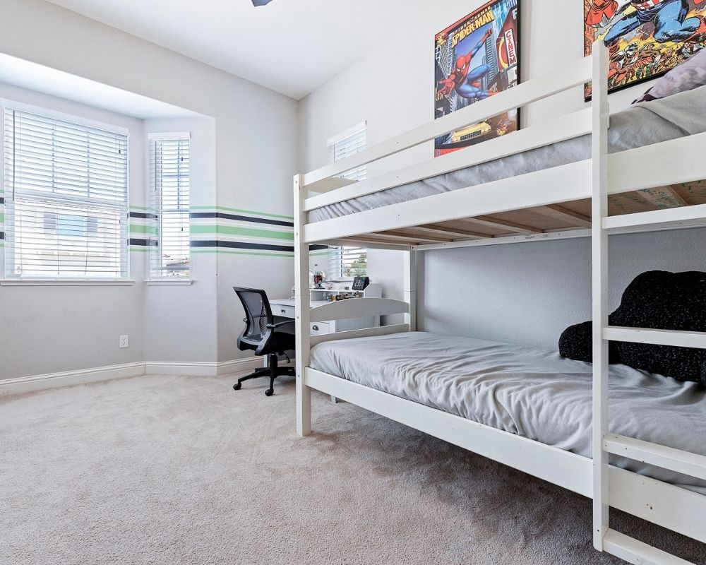 Light gray room with black and green stripes, white bunk bed and white desk.