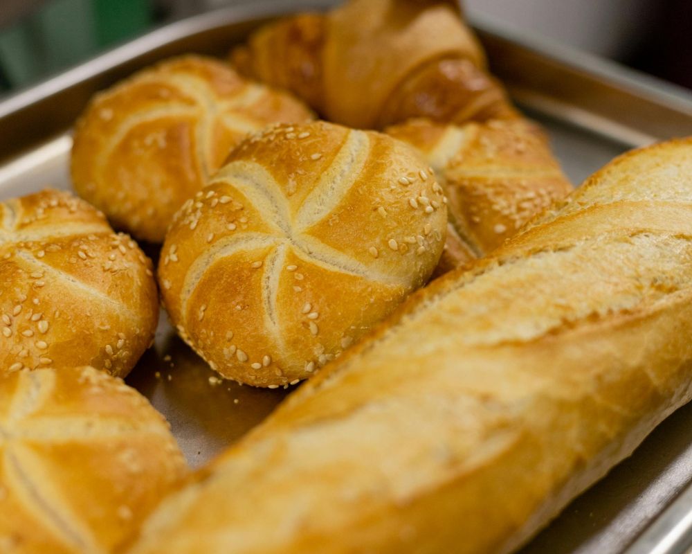 Various types of golden brown bread on a baking sheet.