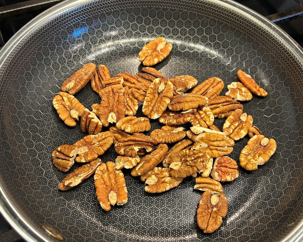 Non stick fry pan with whole pecans being toasted. 