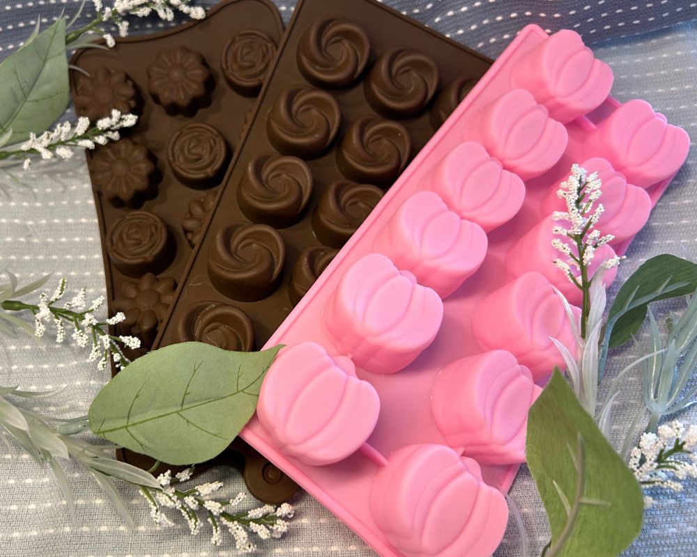 Blue towel background with a pink pumpkin mold and two brown various shape molds. 