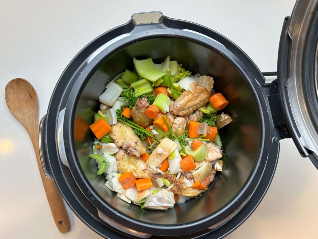 Chicken and vegetables cooking together in a pressure cooker for homemade stock