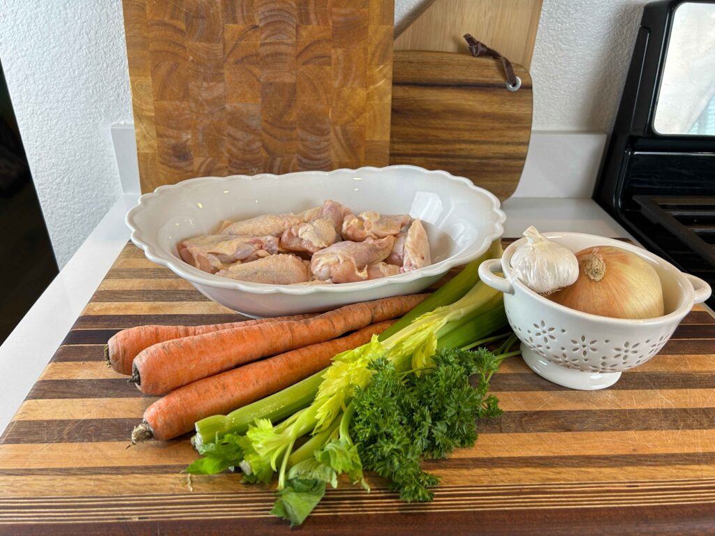 Ingredients for homemade chicken stock including chicken, carrots, celery, onion, and herbs