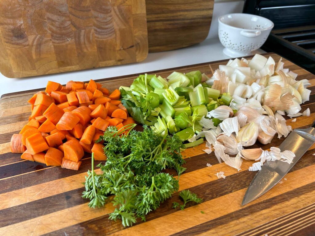 Chopped carrots, celery, onion, and herbs prepared for chicken stock