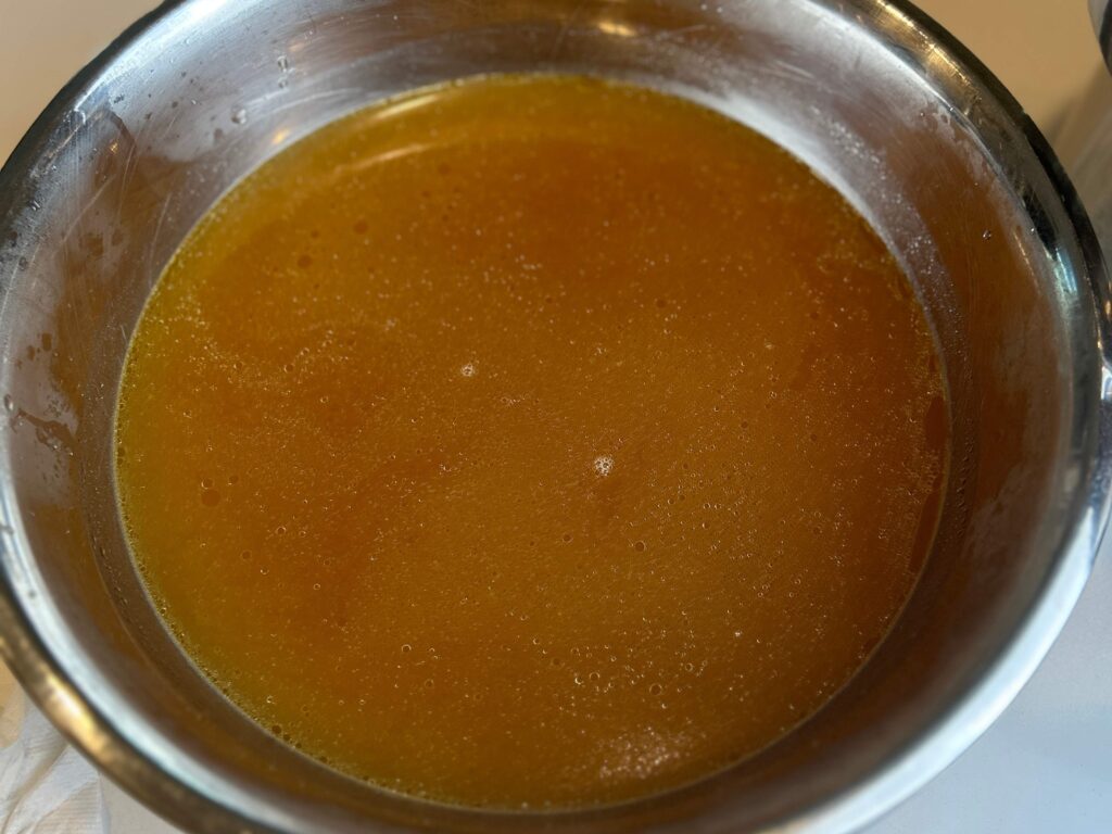 Clear homemade chicken stock in a bowl after straining