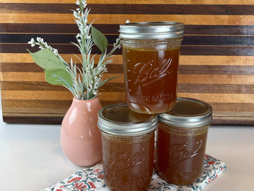 Homemade chicken stock stored in mason jars on a kitchen counter