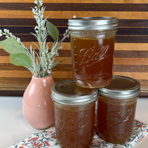 Homemade chicken stock stored in mason jars on a kitchen counter